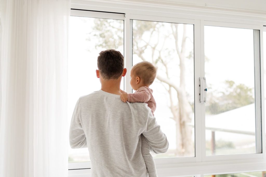 un home amb un nadó mirant per la finestra