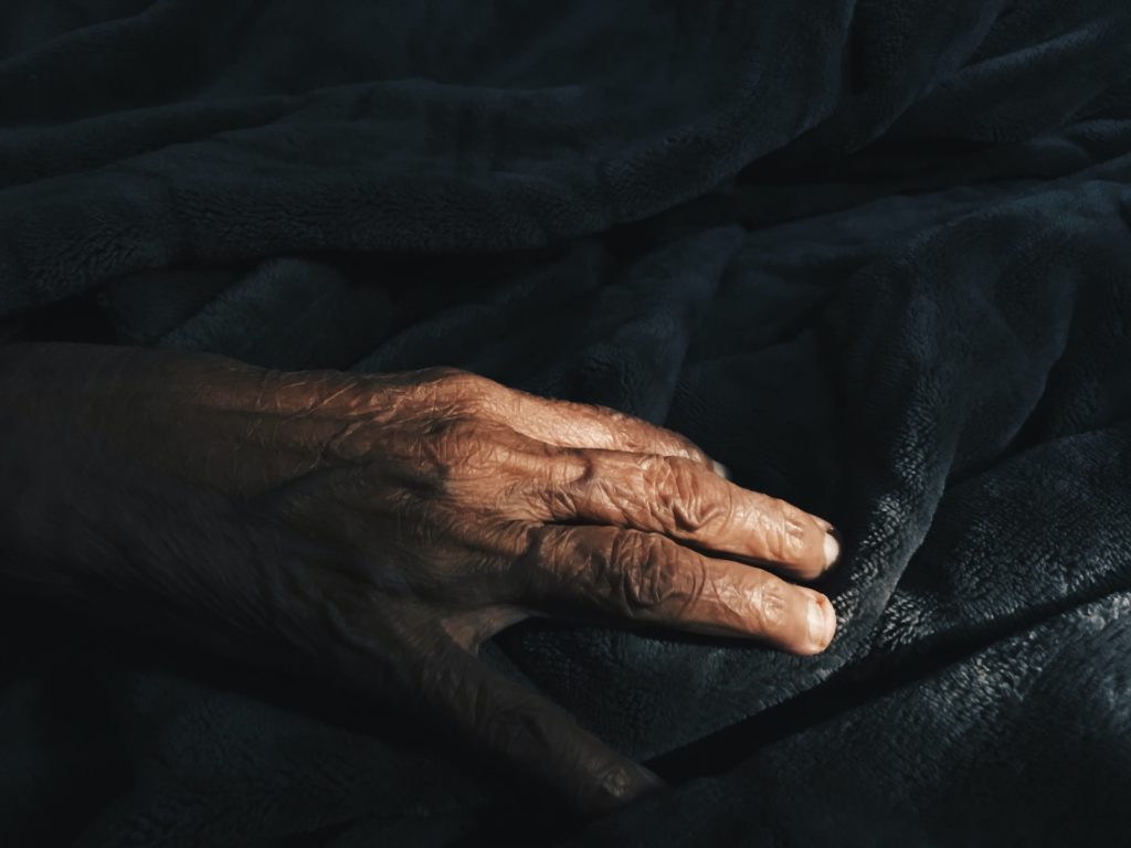 Una mà d'una persona gran a un llit