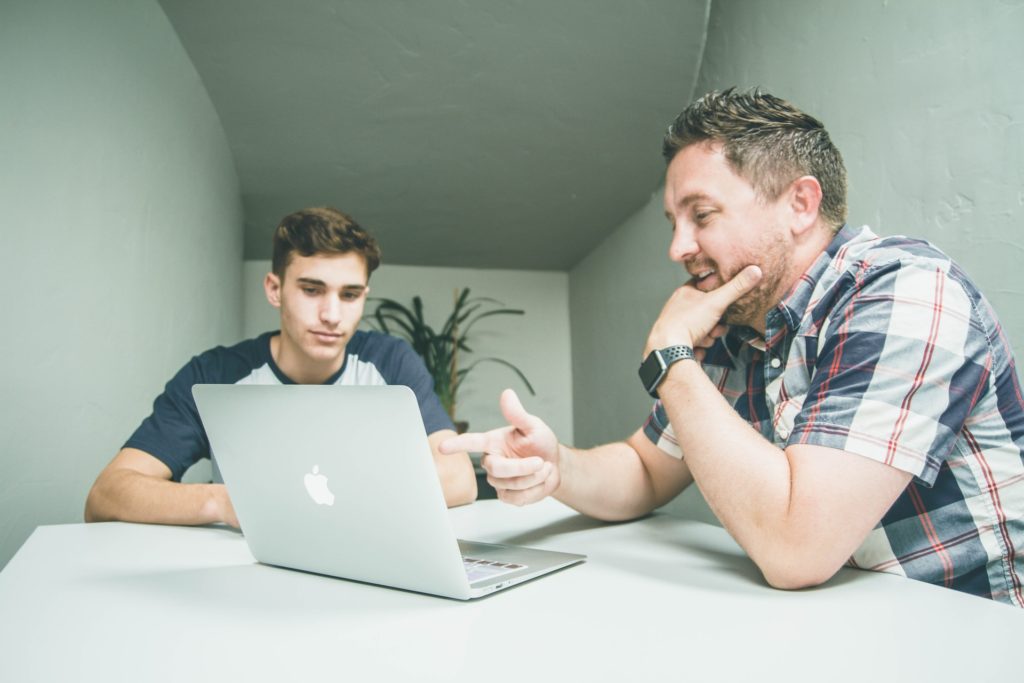 Un jove aprenent amb un home davant l'ordinador