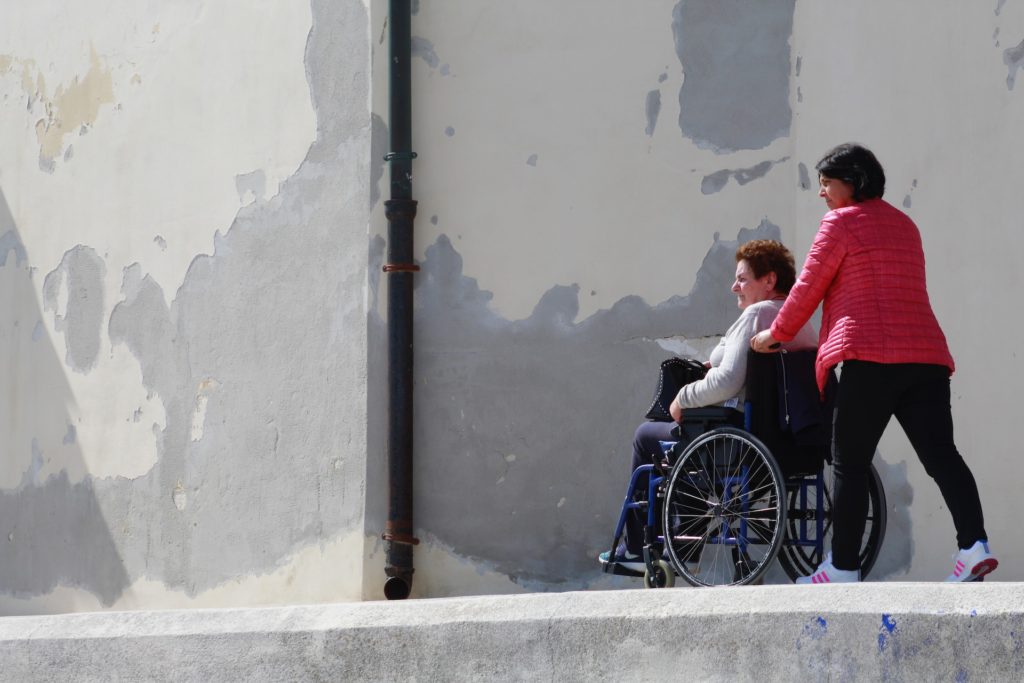 Una dona empenyent la cadira de rodes d'una altra dona gran
