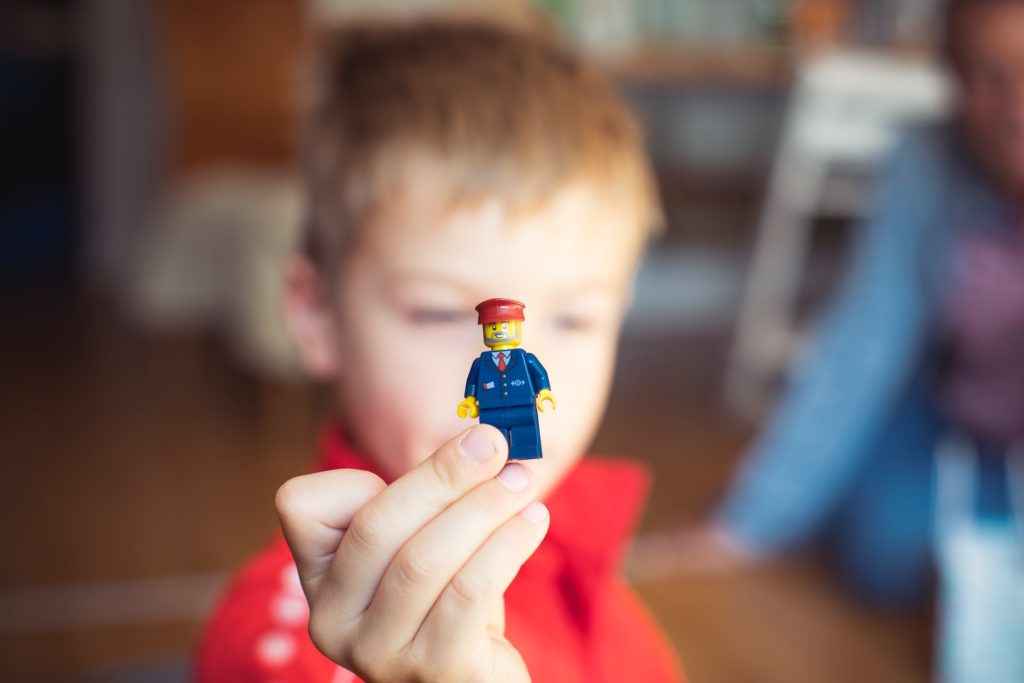 Un nen sosté un ninot de Lego vestit com un carter