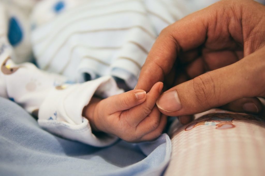 Una persona agafant la mà d'un nadó